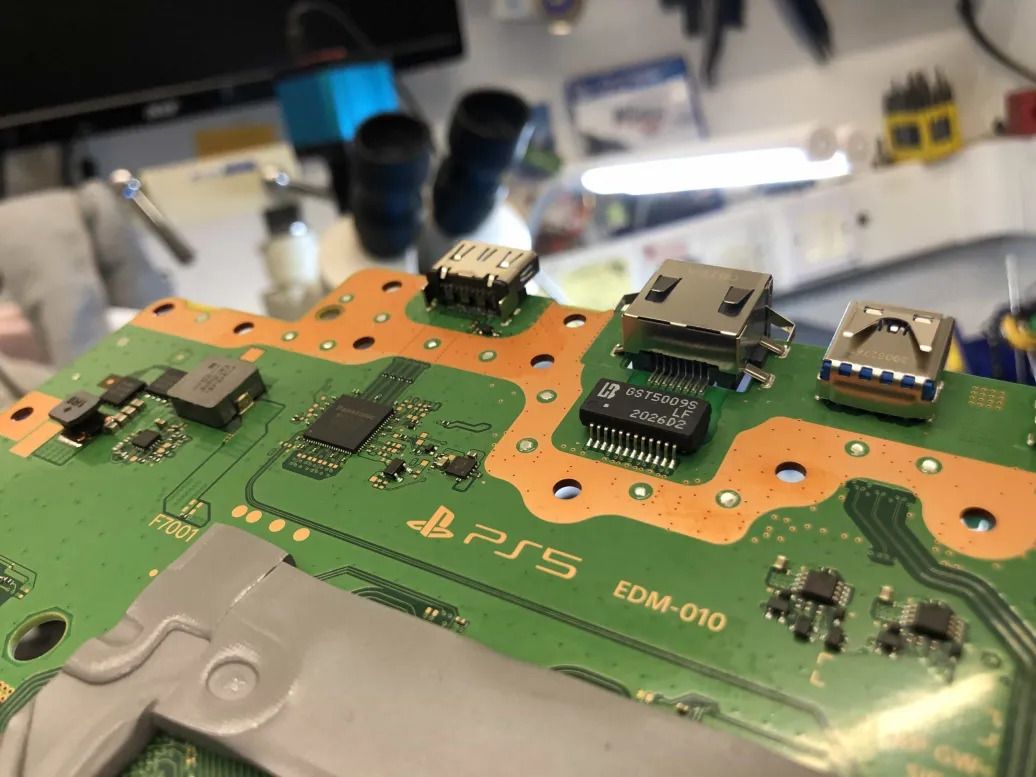 Close-up of a game console circuit board with its ports, in a repair workshop