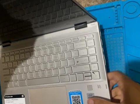 A silver laptop with its keyboard showing on a blue repair mat