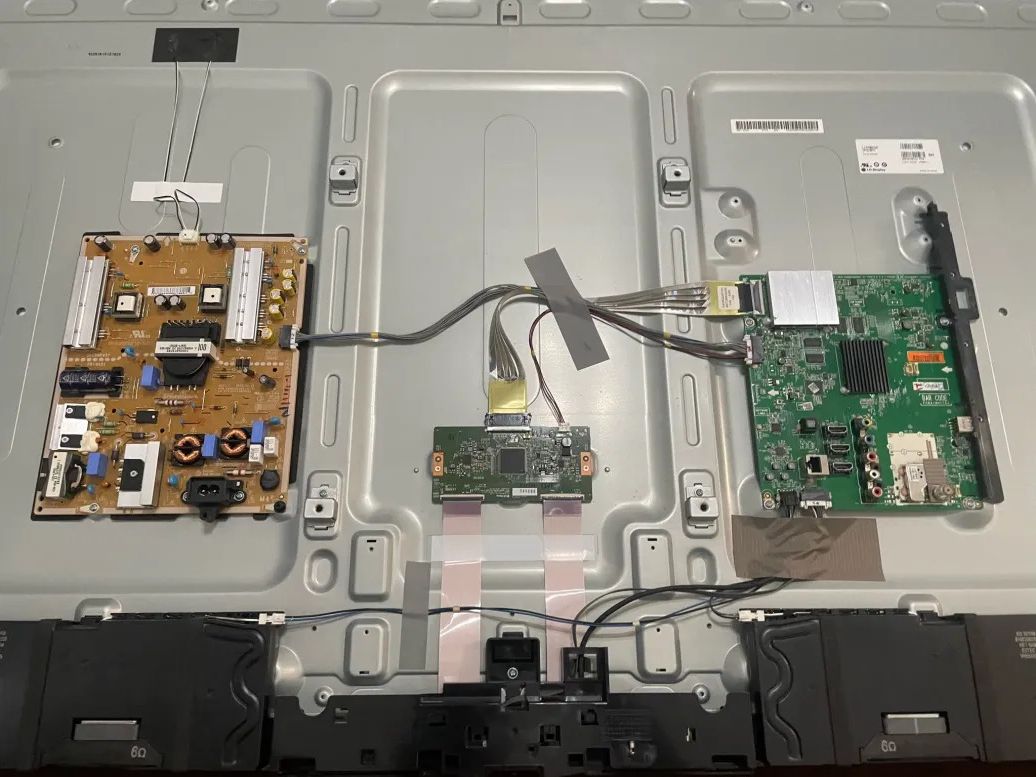 The back of a TV opened up to show its power supply, main board and cables